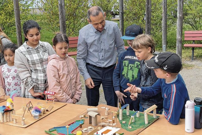 Roland Ledwa, Geschäftsführer der Wohnungsgesellschaft Riesa, lässt sich von den Hortkindern der Grundschule ihre kreativen Modelle für einen neuen Spielplatz erklären.