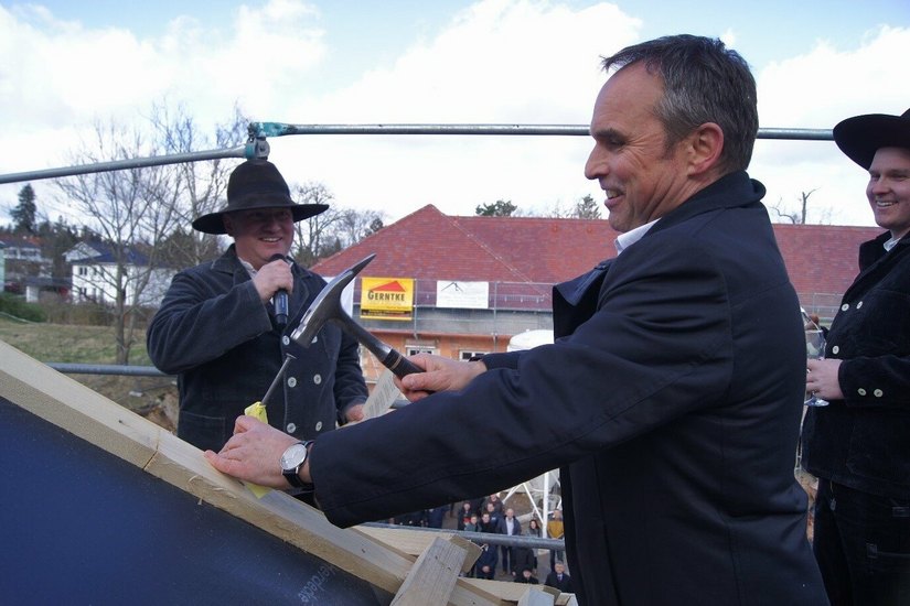 Hentschke Bau-Geschäftsführer Thomas Alscher schlägt symbolisch den letzten Nagel ins Dachgebälk.