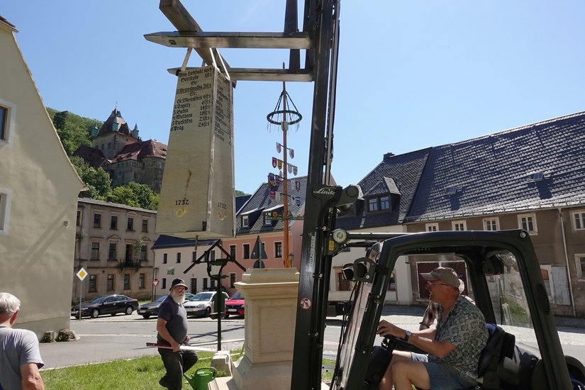 Mitglieder des örtlichen Heimatvereins helfen, um den schmucken Meilenstein unterhalb der Stadtverwaltung aufzustellen.