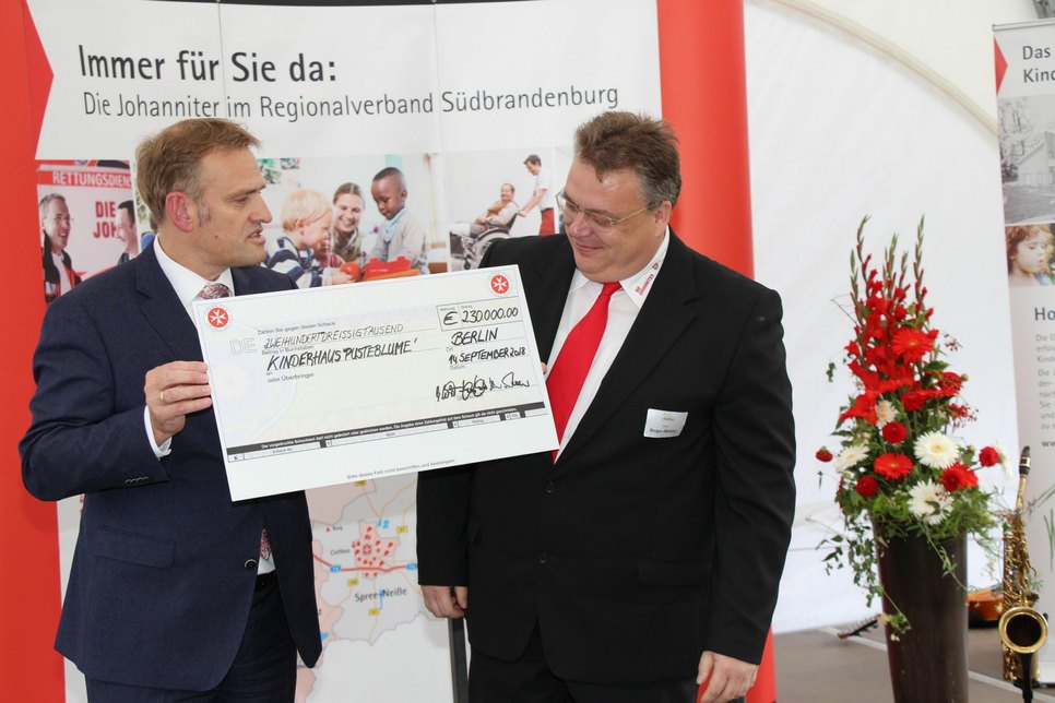 Jörg Lüssem (Johanniter Bundesvorstand) übergibt Andreas Berger-Winkler (Johanniter Regionalvorstand) einen Scheck üvber 230.000 Euro aus Bundesmitteln.