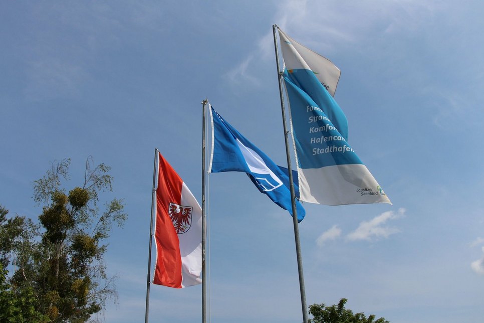 Wie damals 2019 weht auch im Jahr 2022 die »Blaue Flagge« (Mitte) am Senftenberger See am Strand von Großkoschen.
