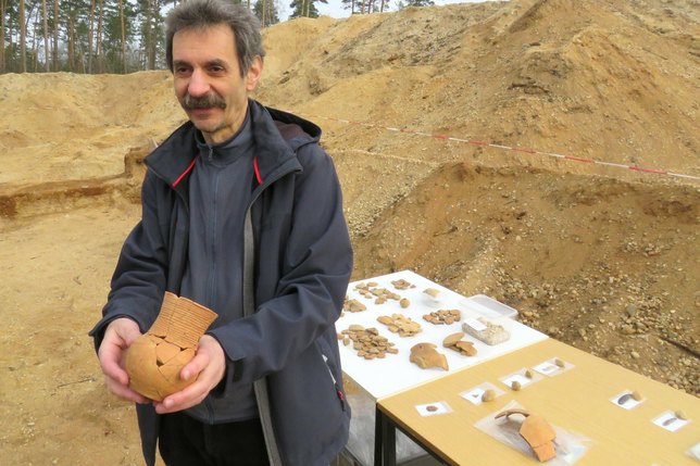 Dr. Harald Stäuble vom Landesamt für Archäologie hält einen besonderen Fund in seinen Händen. Es handelt sich um eine Schnurkeramik, sie stammt aus der Zeit zwischen 2750 und 2200 v.Chr., auf dem Tisch weitere Teile der Ausgrabungen bei Ottendorf-Okrilla. Foto: Matthias Stark