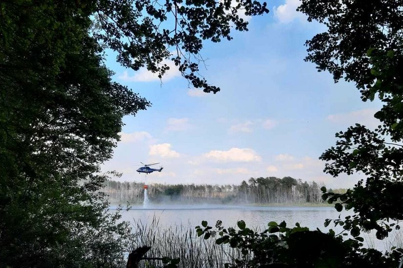 Zwei Hubschrauber helfen bei der Brandbekämpfung und schöpfen Wasser aus einem See.