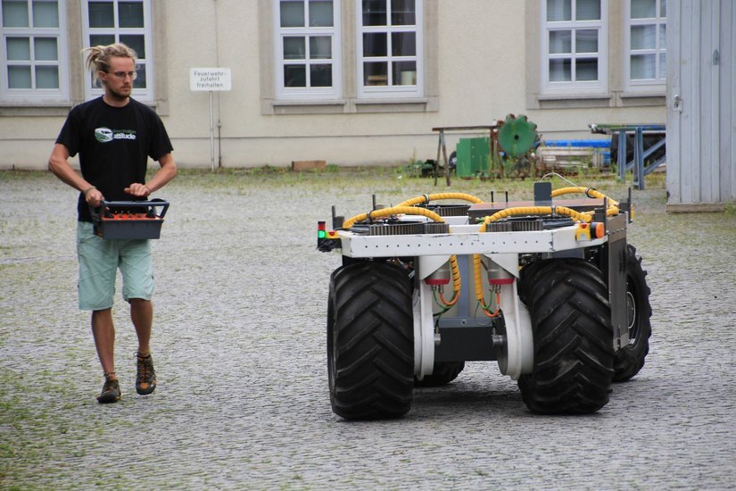 Student Peter Bendix steuert den ELWOBOT. Beim Einsatz in der Obstplantage fährt der Roboter automatisch und trägt große Kanister auf seinem Rücken.              Fotos: Schramm