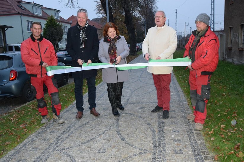 Mitarbeiter der Firma Pasora halten das grün-weiße Band. Der Fachbereichsleiter Bau Dietmar Wolf, Sandra Pasora und der Oberbürgermeister Torsten Ruban-Zeh schneiden es durch.