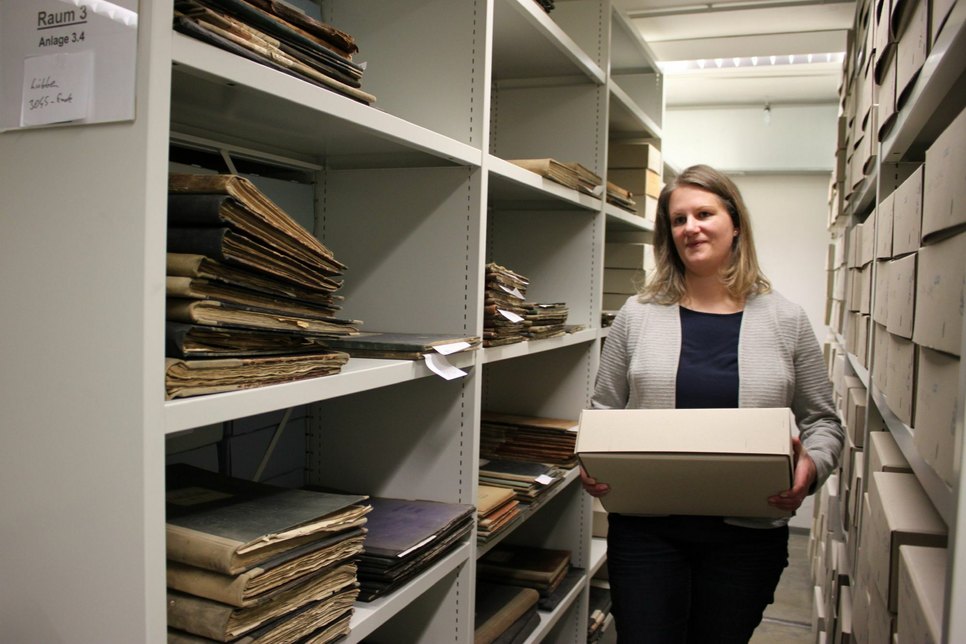 Stadtarchivarin Stephanie Tonke im Archiv im Bürgerhaus-Keller mit einer sogenannten Archivbox, die um bis zu 5 Kilogramm schwer sein kann.  Foto: agu