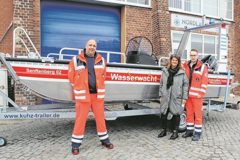 Aron Trippner, Kreisleiter der Wasserwacht, Anett Heyne, Teamleiterin Verbandsarbeit und Felix Lange, Ortsgruppenleiter Wasserwacht Senftenberg, (v.l.) nahmen das neue Rettungsboot in Rostock in Empfang.