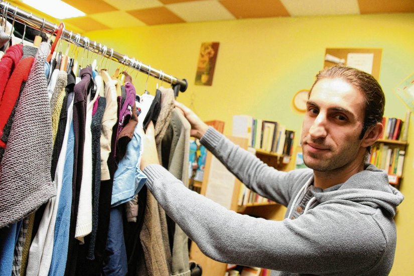 Tarik Dappous (27) sortiert im Kost-Nix-Laden Bekleidung ein. Der Syrer hilft seit einiger Zeit als Dolmetscher. Der Laden setzt sich bewusst kritisch mit dem Gesellschaftsphänomen Kapitalismus auseinander und bietet eine Alternative dazu an. Foto: jho