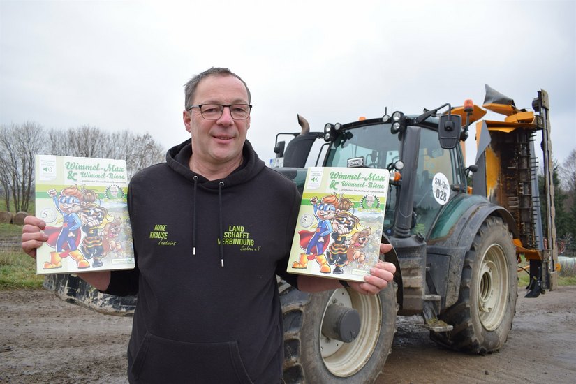 Landwirt Mike Krause hält die Wimmelbücher, die an Kinder gespendet werden sollen, in den Händen.