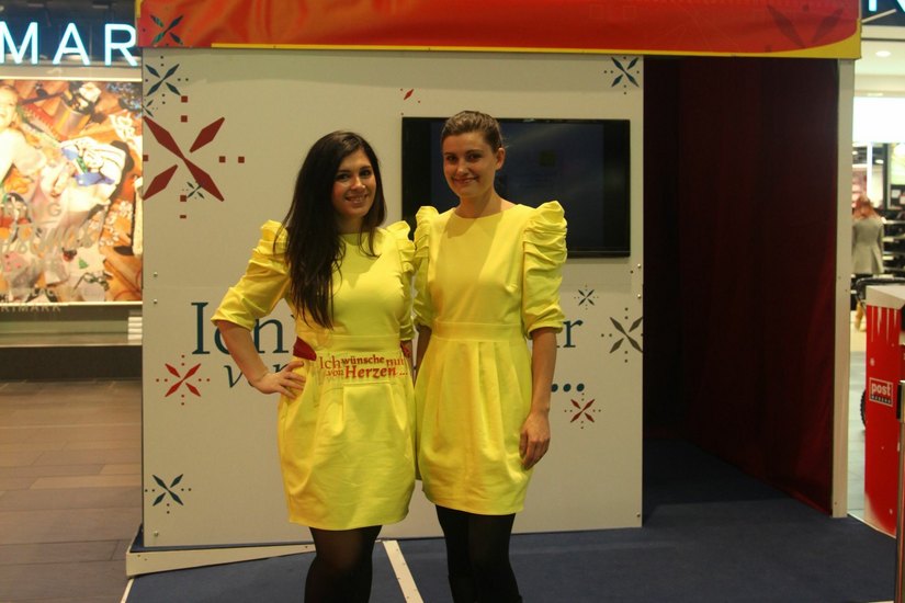 Die Wunschbox steht bis 12. Dezember in der Centrum Galerie. Mit ihren gelben Kleidern sind die Betreuerinnen der Aktion vor Ort nicht zu übersehen. Foto: PR/DMG