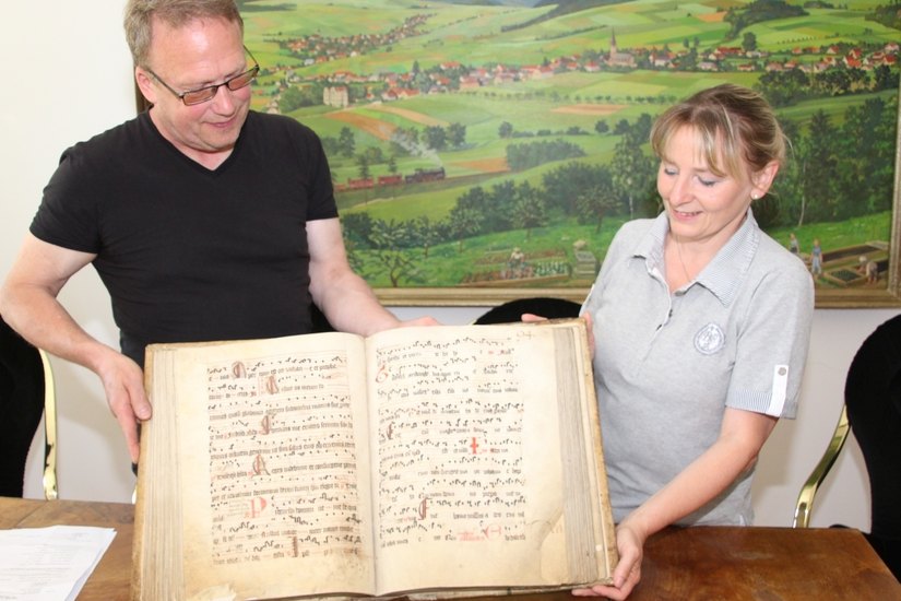 Dirk Keil, Burgwart auf dem Berg Oybin und Gästeführerin Simone Richter zeigen einen der beiden Schätze, das Gesangbuch in Pergamenthandschrift. Foto: Keil