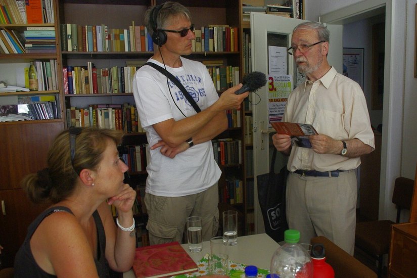 Der ehemalige Vorsitzende des Kunstvereins, Martin Schmidt, spricht mit dem Journalisten Mirko Schwanitz in der Begegnungsstätte. Im Hintergrund sind die Regale mit der Literatur zu sehen, die auf dem Bücherflohmarkt veräußert werden.