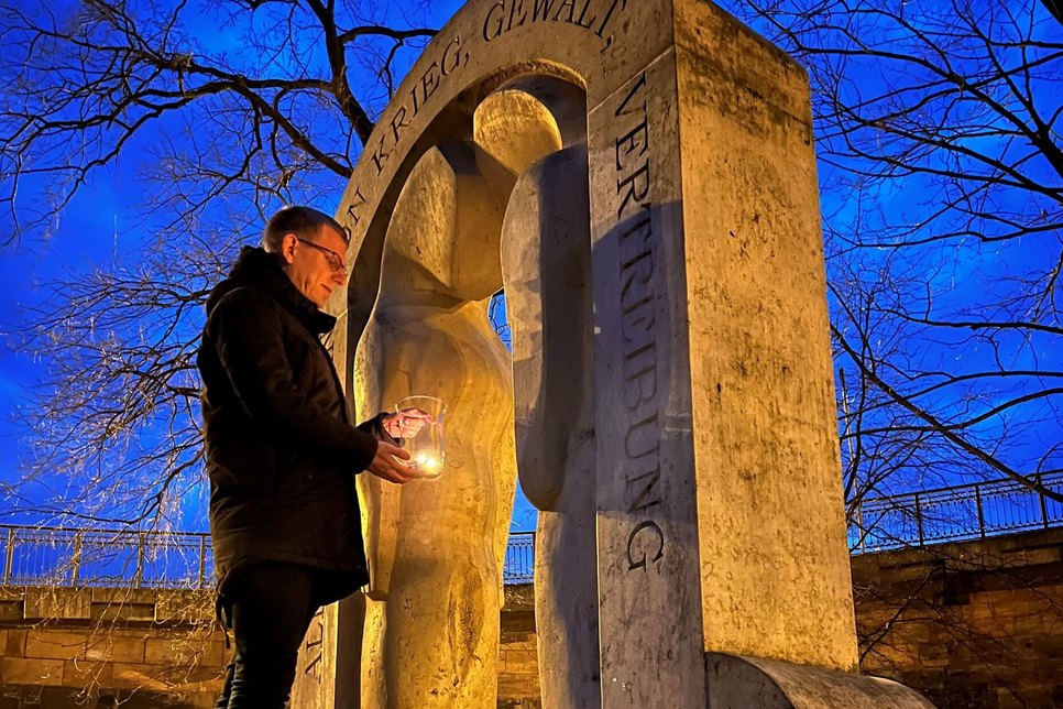 Bürgermeister Markus Dreßler entzündet Kerzen am Denkmal für die Opfer von Krieg, Gewalt und Vertreibung.