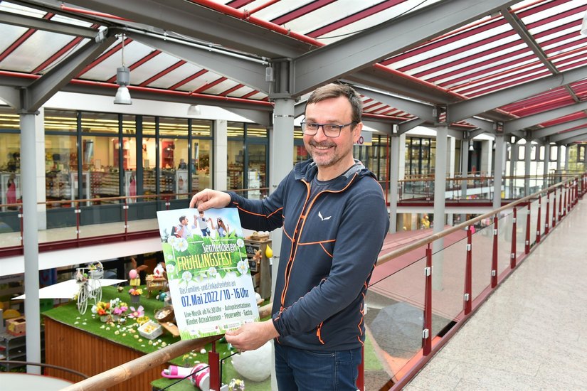 Jens Weser, 2. Vorsitzender des Gewerbevereins Senftenberg, präsentiert im Schlossparkcenter das Plakat zum diesjährigen Frühlingsfest.