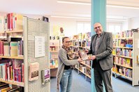Oberbürgermeister Olaf Raschke (r.) übergibt »Called to Teach« aus Provo an die Leiterin der Stadtbibliothek, Laura Siebert (l.).