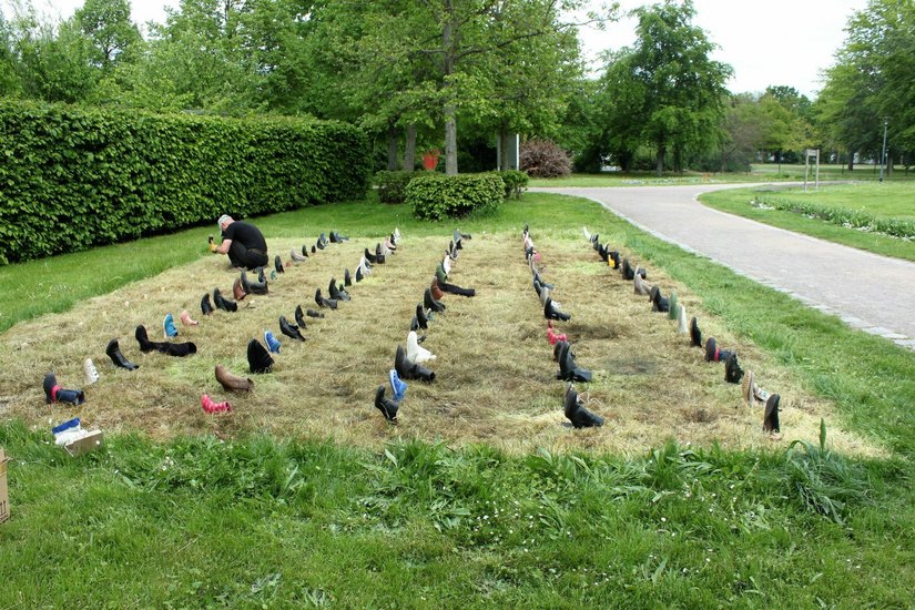 Micha Brendel aus Hohen Neuendorf  (Oberhavel)) zeigt sein Kunstprojekt „Gras über die Sache wachsen lassen“  mit aussortierten Schuhen auf einem verdorrtem Rasen. Foto: „Spektrale 9“/Schirmer
