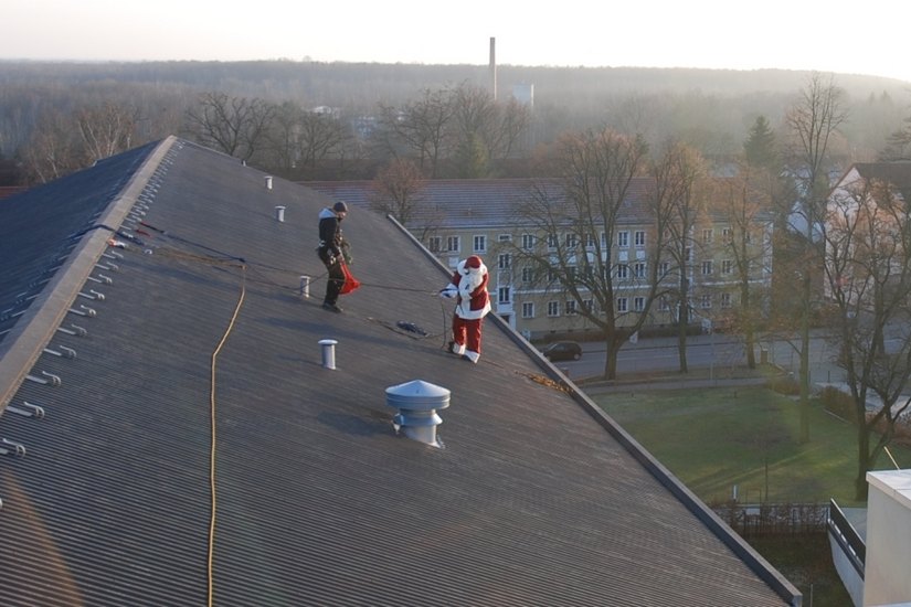 Noch ist der Weihnachtsmann oben auf dem Dach des Klinikums Niederlausitz, gesichert wird er von Pierre Konzag (links).