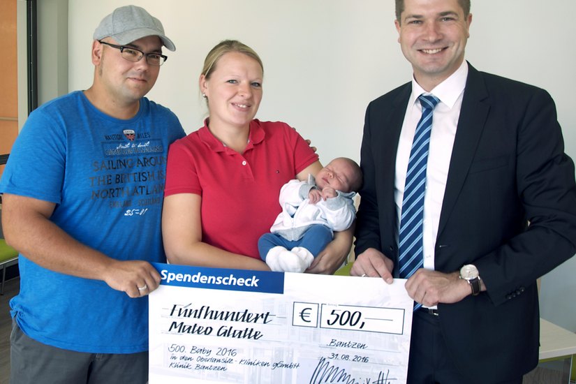 Andreas Wanitzek von der Volksbank Bautzen ist der Gratulant und überraschte die Eltern mit einem Scheck in Höhe von 500 Euro. Foto: Oberlausitz-Kliniken gGmbH