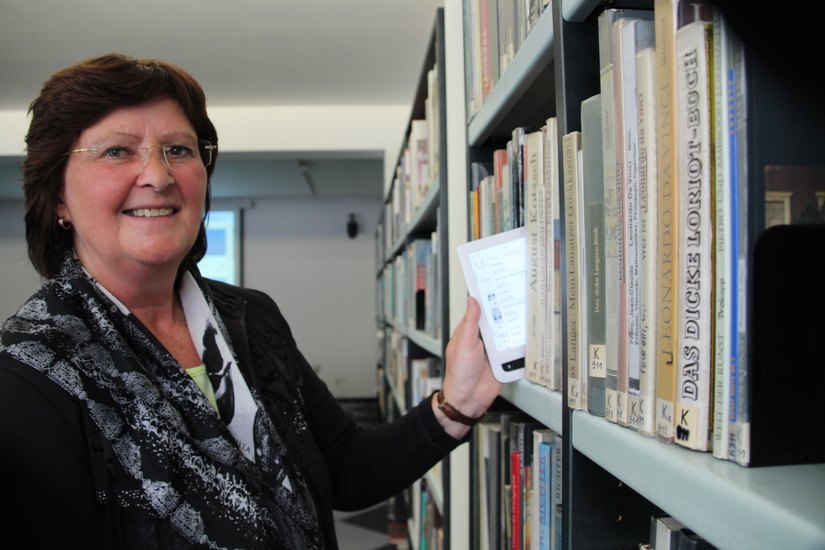 Carola Aschenbach, Chefin der Radebeuler Bibliotheken, zieht (symbolisch) einen E-Reader aus dem Buchregal.      Foto: asc