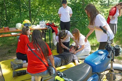 Jugendliche bei der Versorgung eines verletzten Menschen mit Kopfverletzung nach einem Motorradunfall.