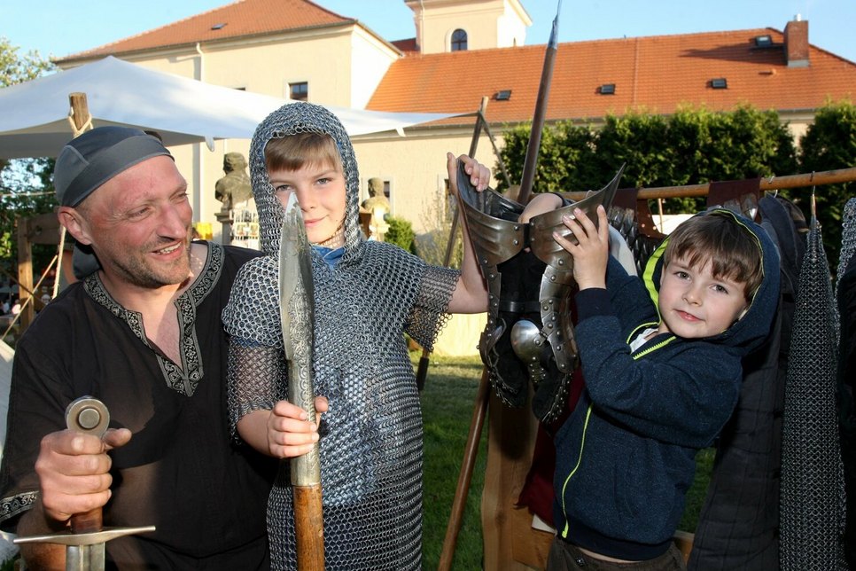 Finn (9) und Bjarne (5) aus Dohna schauen sich im Ritterlager um und probieren eine alte Rüstung an. Gastritter Ronny Dietze aus Rochsburg hilft den beiden Jungen dabei.