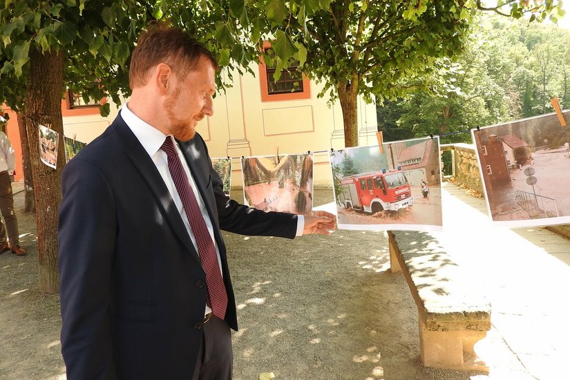 Ministerpräsident Michael Kretschmer betrachtet die Fotos, welche die Flutkatastophe in Weesenstein von 2002 dokumentieren.