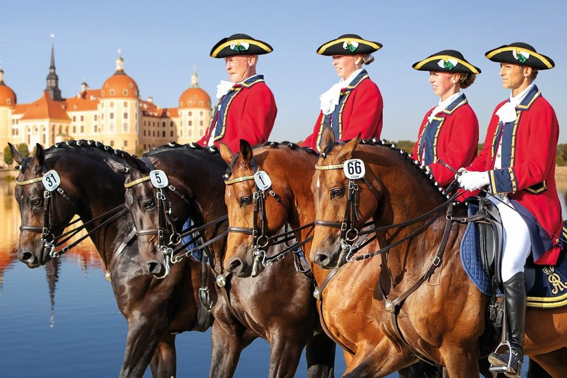 Die Reiter der großen Dressurquadrille in historischen Uniformen vor Schloss Moritzburg.