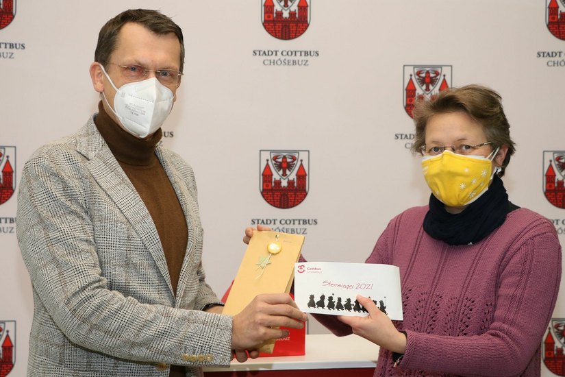 Oberbürgermeister Holger Kelch übergibt die Spenden für die Sternsinger an Gemeindereferentin Gabriele Jarski. Foto: Stadt Cottbus