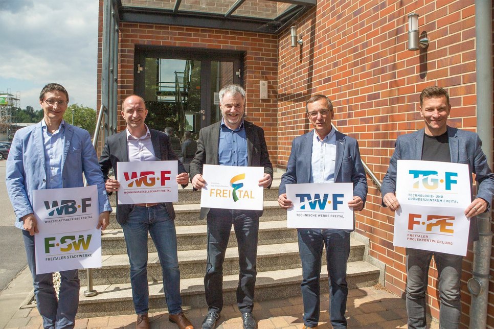Präsentieren ihre neuen Logos: Oberbürgermeister Uwe Rumberg (M.) und (v.l.n.r.) die Geschäftsführer Matthias Leuschner (FSW GmbH/WBF GmbH), Henryk Eismann (WGF GmbH), Jörg Schneider (TWF GmbH) sowie Alexander Karrei (FPE GmbH/TGF GmbH). Foto: Stadt Freital