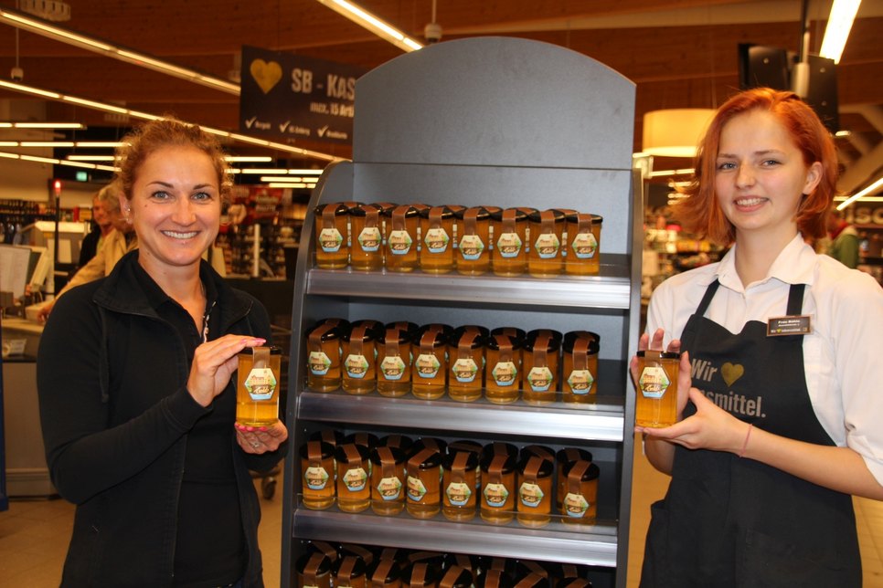 Juliane Scheller und Azubine Lisa Böhle, Bienenbeauftragte im Markt, präsentieren den ersten eigenen Honig, der auf dem Dach des Edeka-Einkaufsmarktes an der Hamburger Straße produziert wurde.