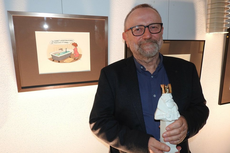 Karikaturpreis-Gewinner Lutz Richter neben seiner Sieger-Zeichnung.