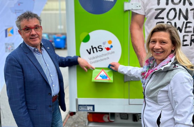 Matthias Weber, Leiter der Volkshochschule Dreiländereck in Zittau, und Ines van Schaik, Projektkoordination des Jugendbüros beim DKSB in Zittau, beim Anbringen des Aufklebers.