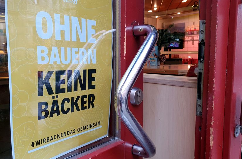"Ohne Bauern keine Bäcker!" #wirbackendas - gemeinsam! ist hinter Glas hinter einer Eingangstür von der Bäckerei Gröger in Pirna zu lesen.