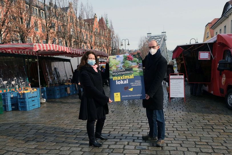 Madeleine Megyesi-Lukaß (Leiterin Wochenmärkte bei der Deutschen Marktgilde) und Dr. Robert Franke (Leiter des Amtes für Wirtschaftsförderung) stellten auf dem Schillerplatz das neue Plakat vor. Foto: B. Albrecht
