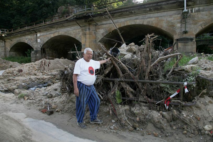 Helmut Paul, Anwohner des Hirschgrundes in Schöna, steht nach der Flut im Juli 2021 vor den Totholz- und Geröllhaufen am unteren Lauf des Mühlgrundbaches. Seit Jahren weist er auf die Beräumung des Baches hin, was seiner Meinung nach das Schadensausmaß deutlich verringert hätte. Foto: D. Förster