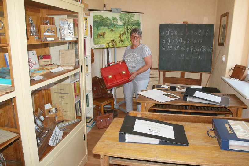 Im historischen Klassenzimmer des Museums zeigt Karin Naumburger wie früher die Bücher in die Schule transportiert wurden - mit dem Ranzen. Fotos: Farrar