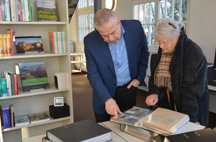 Landrat Michael Geisler blättert mit Frau Heidi Schweizer durch die Chronik der Gemeinde Struppen.