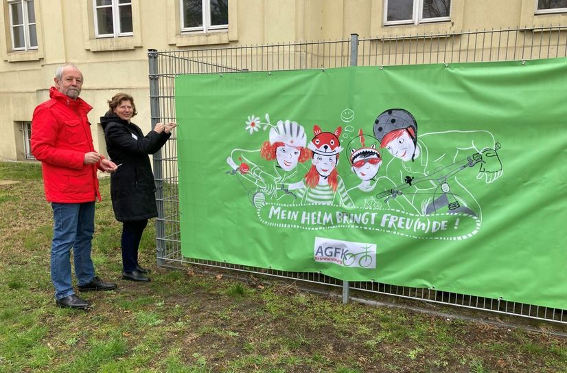 Anbringung des Aktionsmotivs »Mein Helm bringt Freu(n)de« am Landratsamt in Lübben durch Wolfgang Schwerin (Mitarbeiter im Bauordnungsamt für Verkehrliche Infrastruktur) und Heike Zettwitz (Beigeordnete und Dezernentin für Verkehr, Bauordnung, Umwelt und Verbraucherschutz).