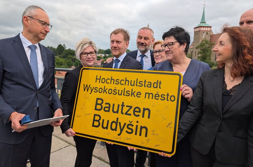 Der Bautzener Oberbürgermeister Karsten Vogt (l.) empfängt das erste - signierte - Ortseingangsschild mit der Ergänzung »Hochschulstadt« von Ministerpräsident Michael Kretschmer (3.v.l.).