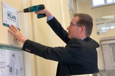 Das kostenfreie öffentliche Brandenburg-WLAN ist nunmehr auch an verschiedenen Standorten der Kreisverwaltung verfügbar. Bau-Dezernent Wilfried Brödno brachte das Hinweisschild im Landratsamt in Senftenberg im Bereich der Sitzungssäle an. Foto: Landkreis/Werner