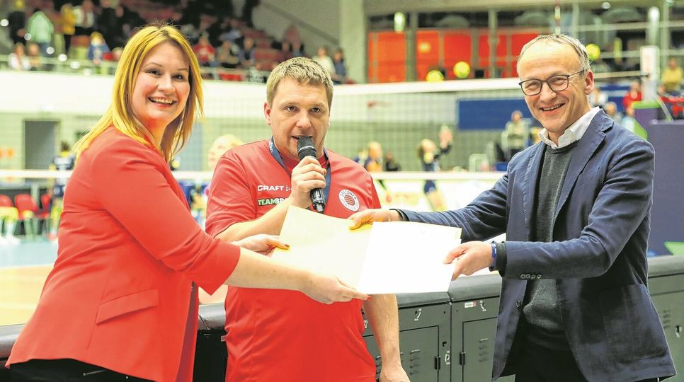 Sportbürgermeister Dr. Peter Lames (r.) übergibt den Fördermittelbescheid im Beisein von Moderator Sebastian Winkler an Sandra Zimmermann.