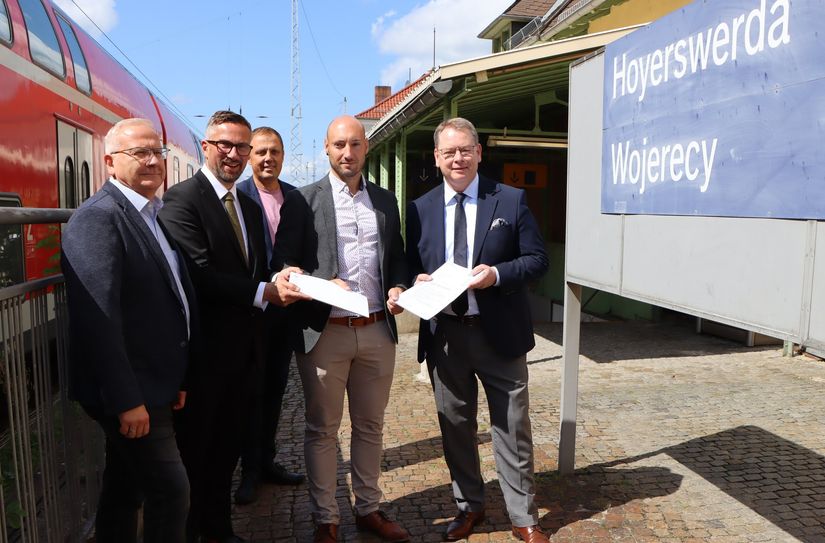 Oberbürgermeister Torsten Ruban-Zeh, Verkehrsminister Martin Dulig, Bürgermeister Mirko Pink, Jan Riedel von DB InfraGO und VVO-Chef Burkhard Ehlen mit dem Förderbescheid am Hoyerswerdaer Bahnhof.