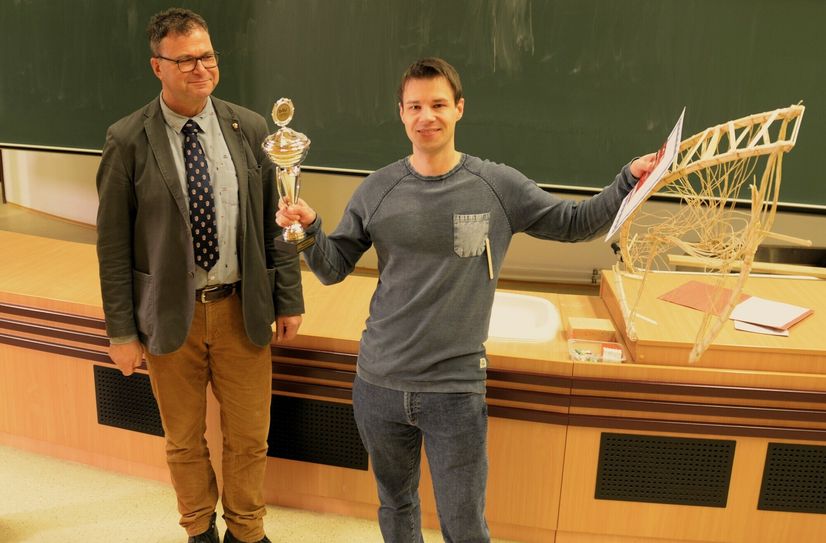 Tim Leuschner, Absolvent aus dem Maschinenbau der BTU, der bei sehr starker Konkurrenz zum dritten Mal den Wettbewerb gewann und mit seiner Brücke den Wanderpokal erkämpfte. Prof. Dr. Sylvio Simon (li.), Leiter der Studiengangs Maschinenbau, nahm die Siegerehrung vor und gehörte zu den ersten Gratulanten.