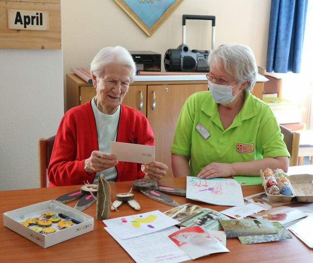 Bewohnerin Elfriede Wilhelm (99) liest mit ihrer Betreuungsassistentin Regine Böhme Osterpost. Foto: PR/ASB Dresden & Kamenz GmbH