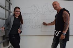 Madeleine Matschke und Jörg Tausch stehen auf dem Gerüst vor einem vorgezeichneten Teil des Wandbildes. In mehreren Nachtschichten des Künstlers nimmt es Form an.