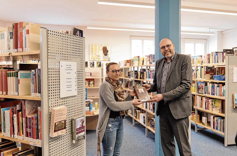Oberbürgermeister Olaf Raschke (r.) übergibt »Called to Teach« aus Provo an die Leiterin der Stadtbibliothek, Laura Siebert (l.).