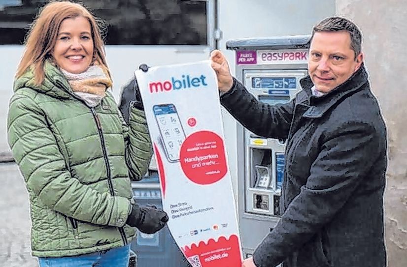 Belinda Zickler, Leiterin Ordnungsamt, und Torsten Stölzner, stadtraum Gesellschaft für Raumplanung, Städtebau &amp; Verkehrstechnik mbH, konnte den ersten Parkscheinautomaten mit den neuen MobiletApp-Hinweisschildern bekleben.  Foto: pm