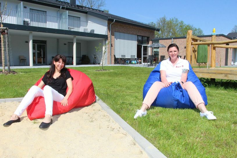 Ariete Fiß (li.), Assistentin der Verlagsleitung, und Einrichtungsleiterin Daniela Konzack (re.) testen im Hof des Kinderhauses die neuen Sitzsäcke. Foto: sts