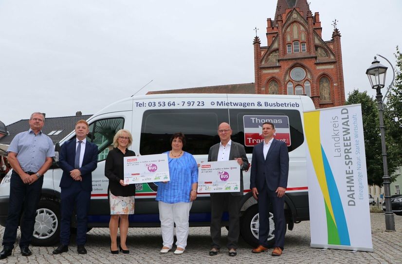 Starteten gemeinsam das neue Flächen-Rufbus-Projekt auf dem Markt in Golßen (v.l.n.r.): Volker Fleischer (Geschäftsführer der Verkehrsgesellschaft Teltow-Fläming mbH), Siegfried Richter (Geschäftsführer der Regionalen Verkehrsgesellschaft Dahme-Spreewald mbH), Landrätin des Landkreises Teltow Fläming Kornelia Wehlan, Bürgermeisterin der Stadt Golßen Daniela Maurer, Landrat im Landkreis Dahme-Spreewald Stephan Loge und Amtsdirektor Unterspreewald Marco Kehling. Im Hintergrund ist das eingesetzte Linietaxi zu sehen.