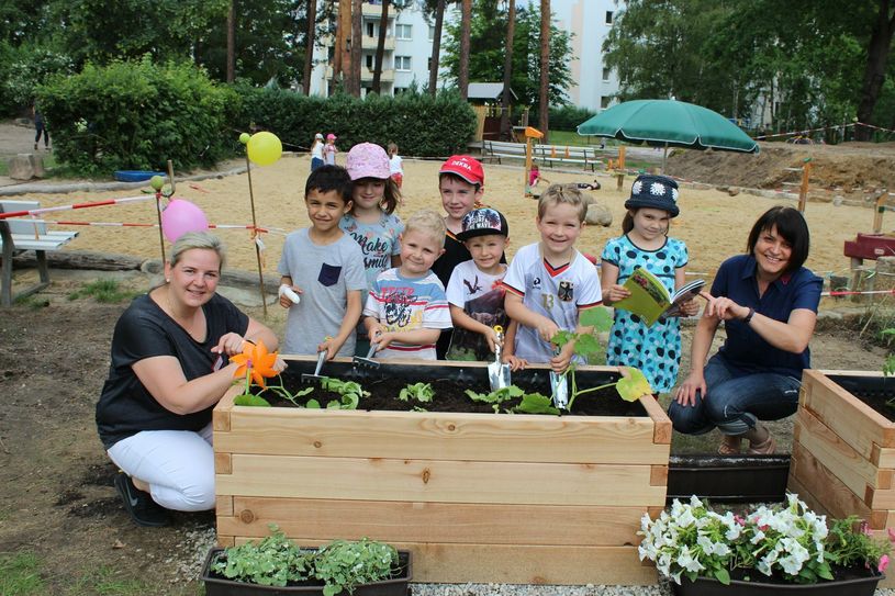 Im Zuge der Baumaßnahmen konnten unter anderem neue Hochbeete und eine Matschanlage eingeweiht werden. Das freute die Kinder und Kita – Leiterin Jana Welsch (blond, lange Haare). Dennoch gibt es noch viel zu tun auf den Außenanlagen. Foto: Silke Richter